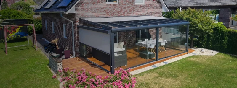Moderner Wintergarten mit Glasdach und Sonnenschutz an Einfamilienhaus im Garten.